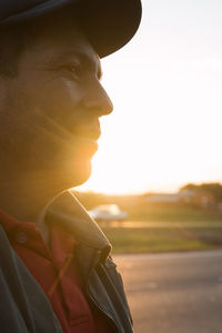 Close-up of man looking away against sky during sunset