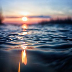 Close-up of water drop against sky during sunset