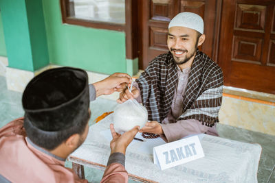 Happy young man giving bag of rice in mosque