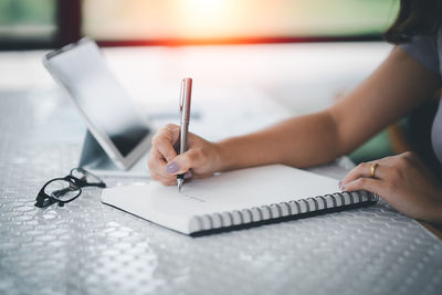 Midsection of woman writing in book