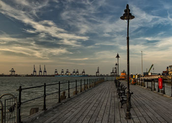 View of pier on jetty in city at sunset