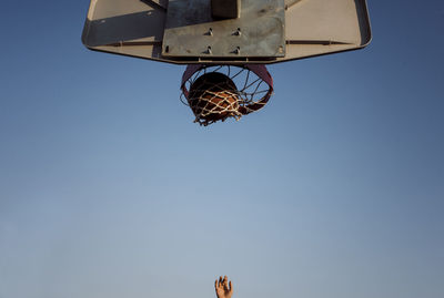 Full length of thoughtful basketball player with ball sitting on court