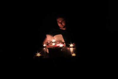 Man reading book in illuminated room at night