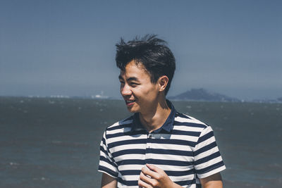 Smiling young man looking away against sky