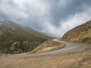 Scenic view of road by mountains against sky