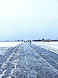 People enjoying on frozen lake ice rink against clear sky