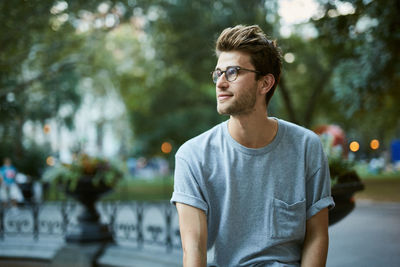 Young man sitting by fountain at park