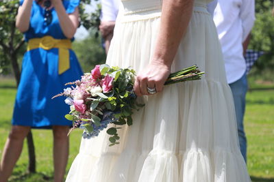 Midsection of bride holding bouquet