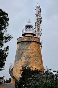 Lighthouse by sea against sky