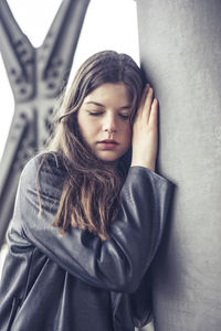 Portrait of young woman standing against wall