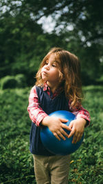 Cute girl holding ball looking away at park