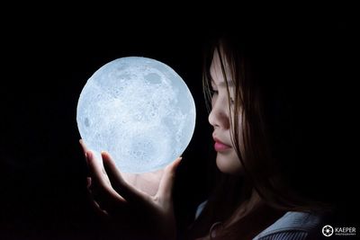 Close-up portrait of woman holding girl over black background