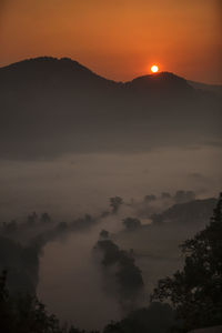 Scenic view of silhouette mountains against orange sky