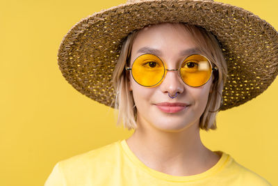 Portrait of woman wearing hat against yellow background