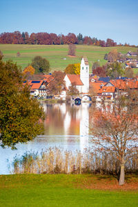 Scenic view of lake by houses against sky