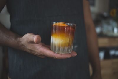 Midsection of man holding iced coffee at cafe