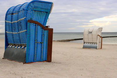 Hooded chairs on beach against sky