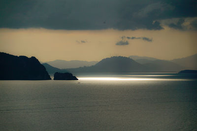 Scenic view of sea and mountains against sky at dusk