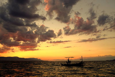 Silhouette sailboat in sea against sky during sunset