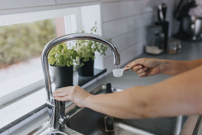 Woman's hands pouring water into measuring spoon