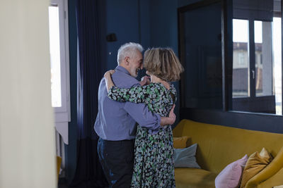 Loving couple smiling while dancing at home