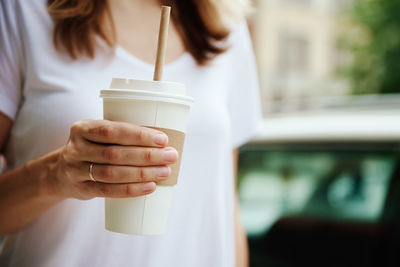 Woman holds paper coffee cup at city street