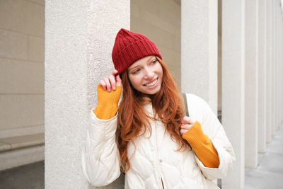 Portrait of young woman standing against wall