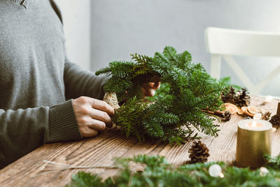 A man at home makes a christmas wreath from fresh spruce branches. decorating your home 