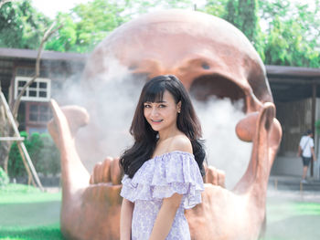 Portrait of smiling young woman standing against skull