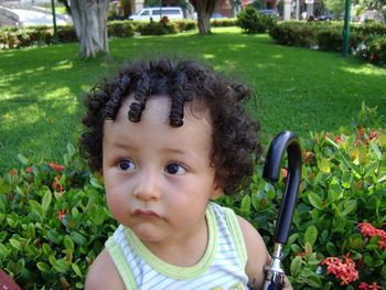 Cute baby boy with curly hair holding umbrella at park