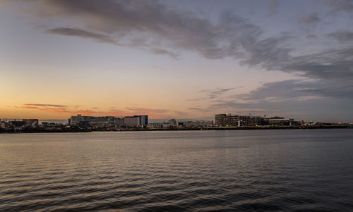 Scenic view of sea by buildings against sky during sunset