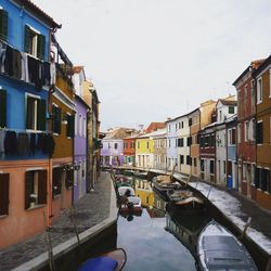 View of canal in city against sky