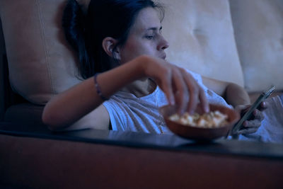 Side view of young woman having food at home