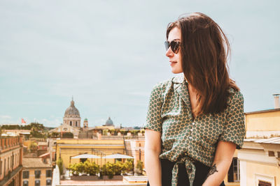 Portrait of young woman wearing sunglasses standing against sky