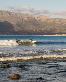 Man surfing in sea against sky