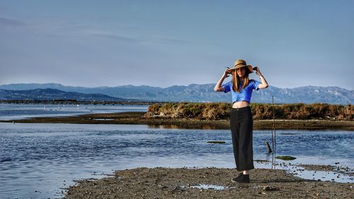 Woman standing at beach against sky