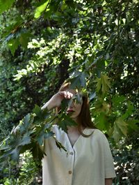 Midsection of woman standing by leaves against tree