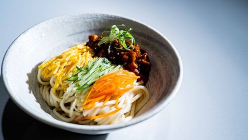 A bowl of dried meat tricolor noodles on the table over white