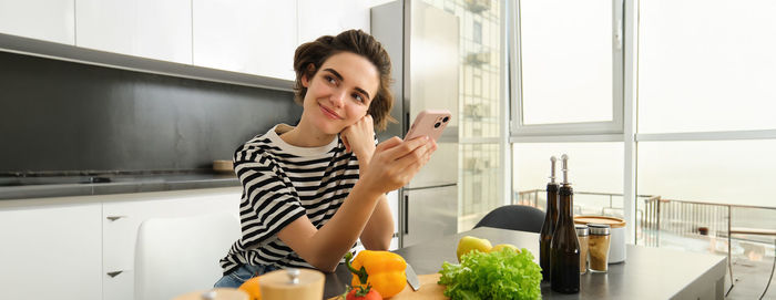 Portrait of young woman using mobile phone at home