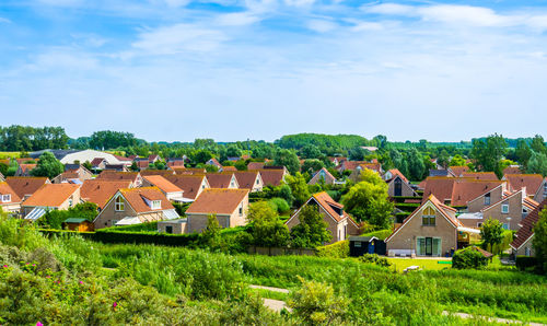 Houses on field by buildings against sky