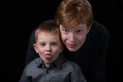 Portrait of father and son against black background