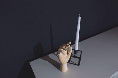 High angle view of wooden hand by candle on table