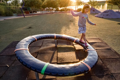 Young girl balances while walking on circle structure at a playground