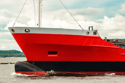 Red ship moored on sea against sky