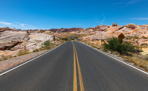 Road leading towards mountains against sky