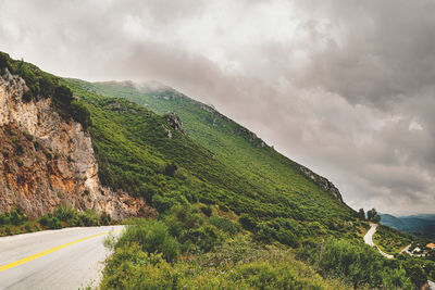 Scenic view of road by mountains against sky