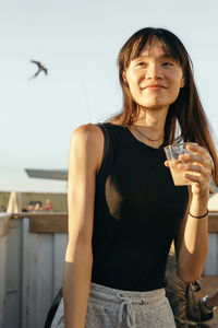 Beautiful young woman standing by drink