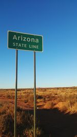 Information sign on landscape against clear blue sky