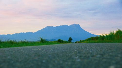 Scenic view of road by mountains against sky