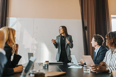 Female business entrepreneur explaining strategies to colleagues in board room at office